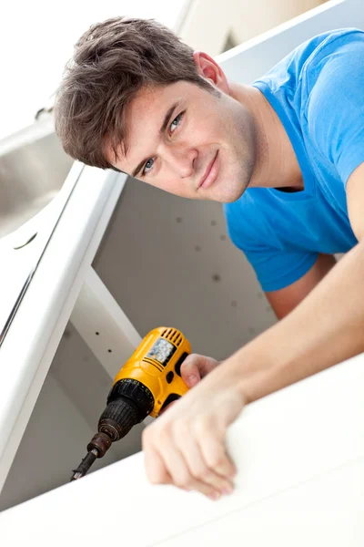 Charismatic man repairing his sink and holding a drill in the ki — Stock Photo, Image