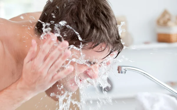 Φωτεινό καυκάσιος άνθρωπος ψεκασμός νερού στο πρόσωπό του, μετά το ξύρισμα σε — Φωτογραφία Αρχείου