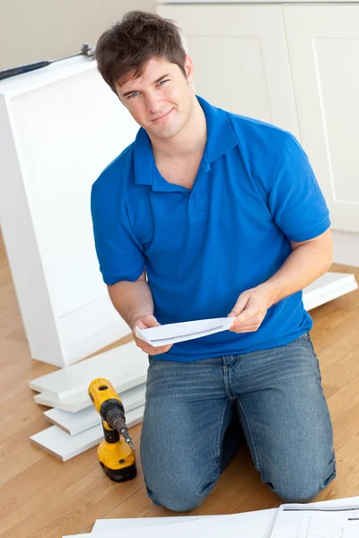 Charismatic young man reading the instructions to assemble furni — Stock Photo, Image