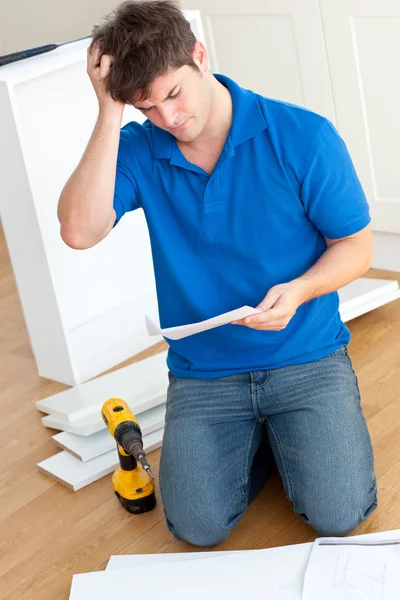 Incomprehensive young man reading the instructions to assemble f — Stock Photo, Image