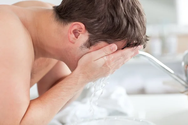 Cute caucasian man spraying water on his face after shaving in t — Stock Photo, Image