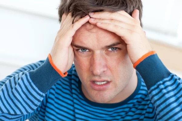 Homem caucasiano com dor de cabeça na sala de estar — Fotografia de Stock