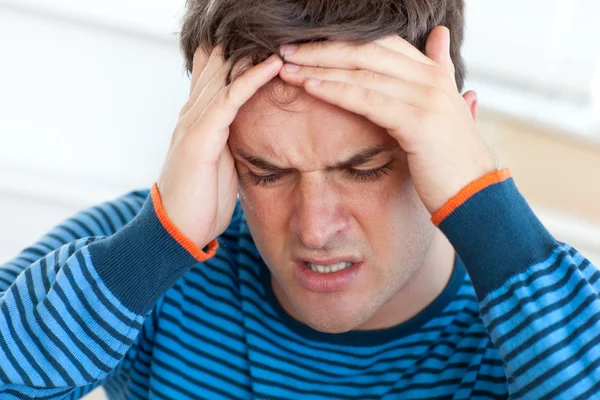 Knappe man met een hoofdpijn in de woonkamer — Stockfoto