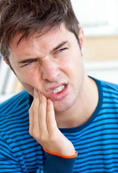 Несчастный кавказский мужчина с зубной болью в гостиной — стоковое фото