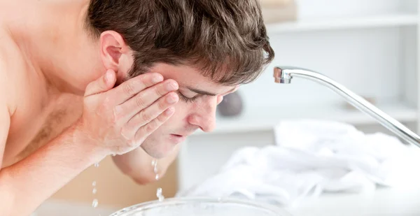 Joven caucásico hombre rociando agua en su cara después de afeitarse en —  Fotos de Stock