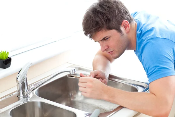 Uomo concentrato che ripara il lavandino in cucina — Foto Stock