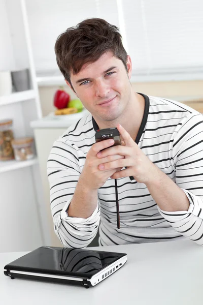 Un homme souriant envoie un message texte avec son téléphone portable devant — Photo