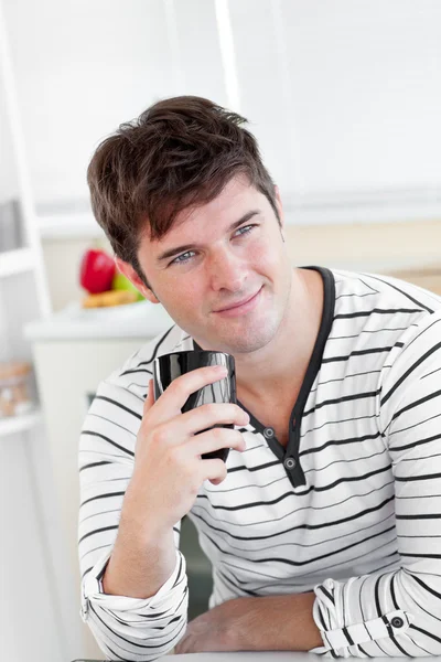 Харизматичный молодой человек пьет кофе на кухне — стоковое фото