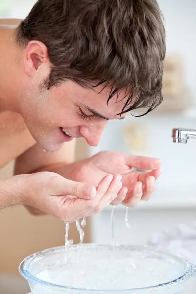 Sorrindo caucasiano homem pulverizando água em seu rosto depois de barbear i — Fotografia de Stock