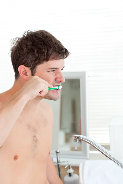 Good-looking young man brushing his teeth in the bathroom — Stock Photo, Image