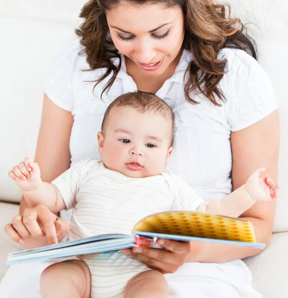 Aufgeweckte Mutter zeigt ihrem niedlichen kleinen Sohn Bilder in einem Buch — Stockfoto