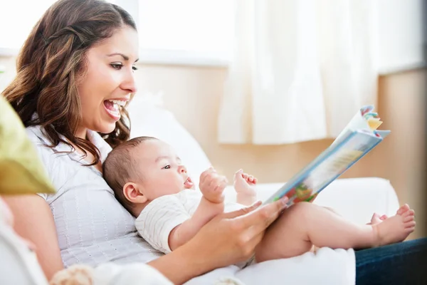 Encantadora madre mostrando imágenes en un libro a su pequeño y lindo hijo — Foto de Stock