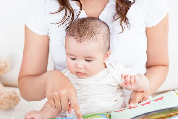 Mãe atenta mostrando imagens em um livro para seu filhinho bonito — Fotografia de Stock