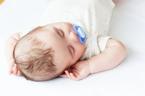 Retrato de um bebê adorável com uma chupeta dormindo em uma cama — Fotografia de Stock
