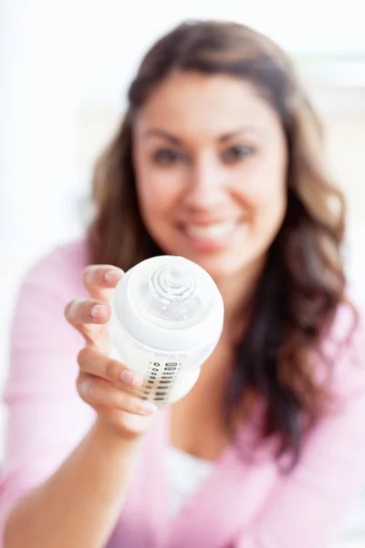 Close-up of a smiling young mother holding a feeding-bottle — Stock Photo, Image