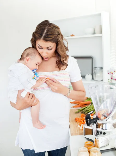 Caring mother preparing food for her adorable baby in the kitche — Stock Photo, Image