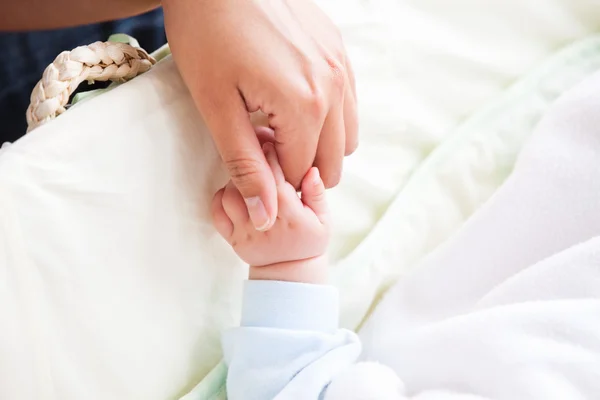 Крупный план молодой матери, держащей своего ребенка за руку — стоковое фото