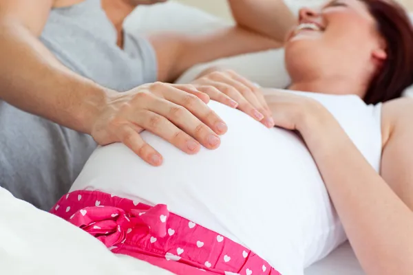Mulher grávida caucasiana alegre deitada na cama com o marido — Fotografia de Stock