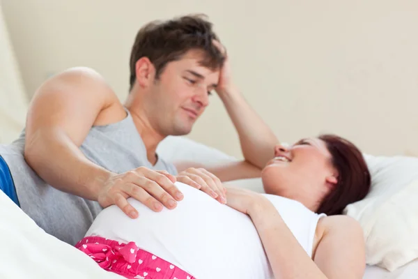 Freudig schwangere Frau liegt mit ihrem Mann im Bett — Stockfoto