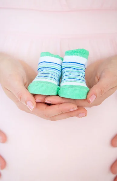 Close-up of a caucasian pregnant woman holding baby shoes and of — Stock Photo, Image