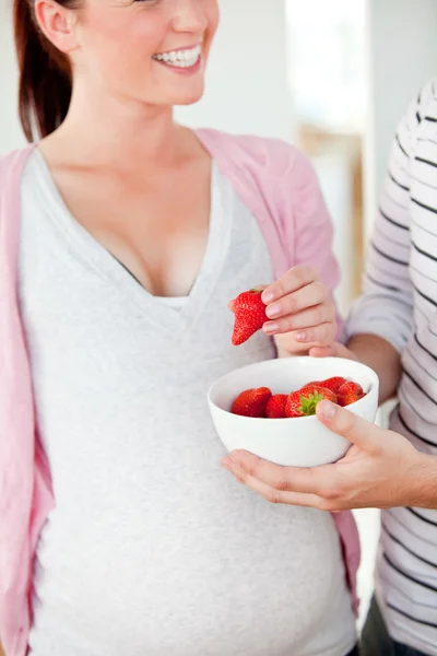 Bliska uśmiechający się kobieta w ciąży, jedzenie truskawek i z — Zdjęcie stockowe