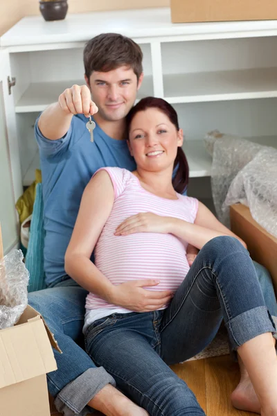 Szczęśliwa para spodziewa się dziecka, siedząc na podłodze i gospodarstwa t — Zdjęcie stockowe