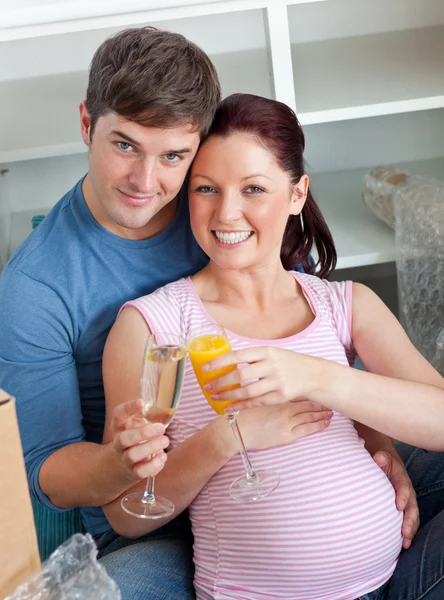 Счастливая пара ожидает ребенка, пьющего и сидящего на полу — стоковое фото