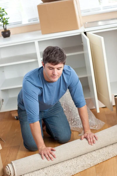 Handsome man rolling a carpet out — Stock Photo, Image