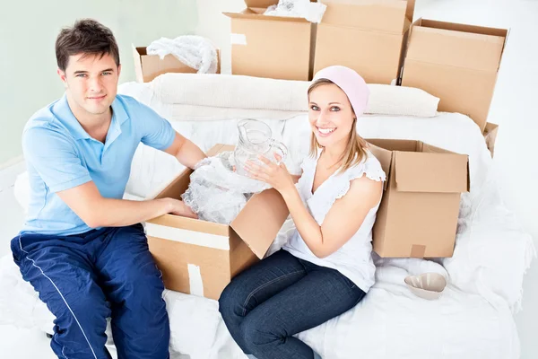 Sorrindo jovem casal desempacotando caixas com óculos — Fotografia de Stock