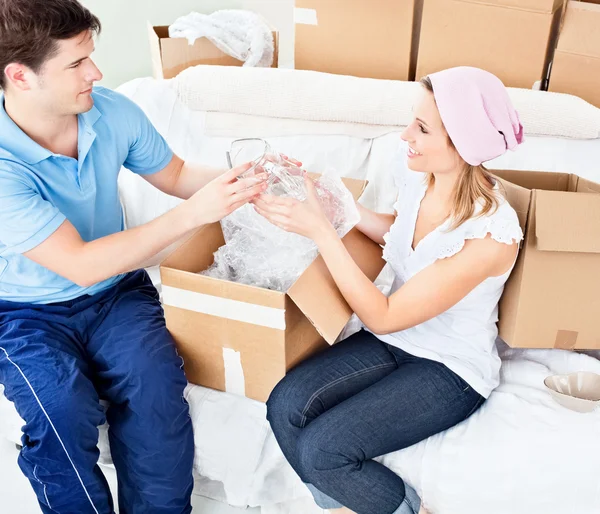Affectionate young couple unpacking boxes with glasses — Stock Photo, Image