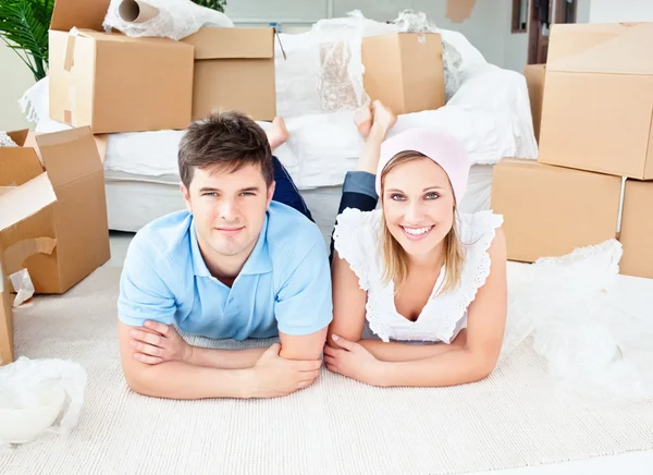 Smiling couple lying on the floor after unpacking boxes — Stock Photo, Image