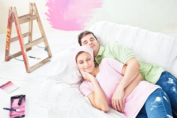 Ενθουσιασμένος ζευγάρι ξαπλωμένο στον καναπέ μετά την ζωγραφική τους νέα αίθουσα — Φωτογραφία Αρχείου