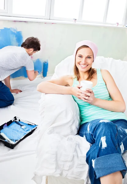 Smiling woman sitting on the sofa looking at the camera — Stock Photo, Image