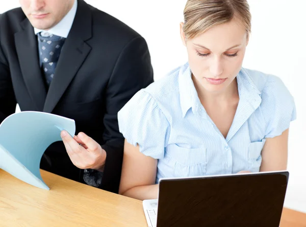 Couple of frustrated businesspeople reading a folder and using a — Stock Photo, Image