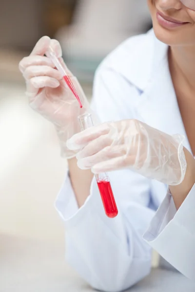 Close-up of a smiling scientist holding a pipette and a test tub — Stock Photo, Image