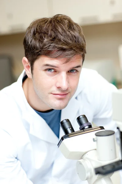 Hombre guapo científico usando un microscopio — Foto de Stock
