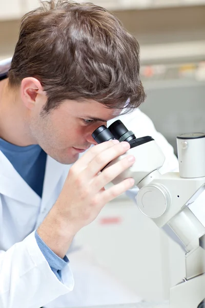 Scientifique masculin sérieux regardant à travers un microscope — Photo