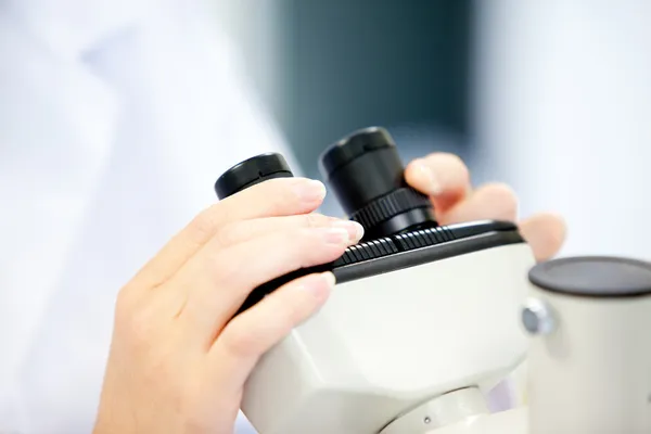 Gros plan d'une scientifique qui regarde à travers un microscope — Photo
