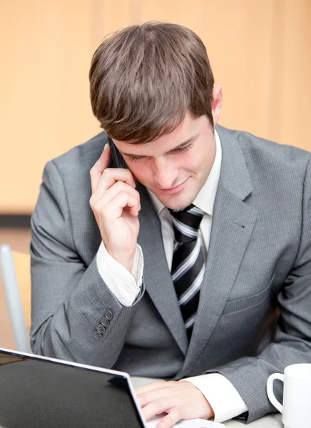 Koncentrované podnikatel používat svůj notebook při rozhovoru na telefonu — Stock fotografie