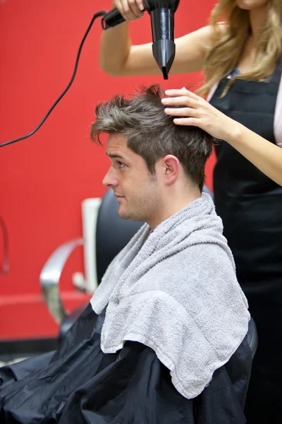 Cabeleireiro fêmea secando o cabelo de seu cliente masculino — Fotografia de Stock