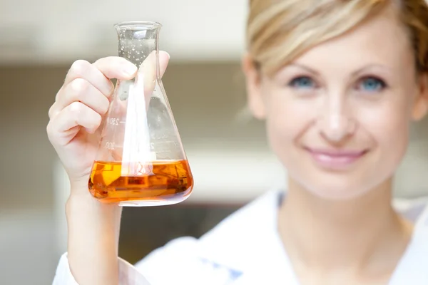 Close-up of a female scientist holding an erlenmeyer and smiling — Stock Photo, Image