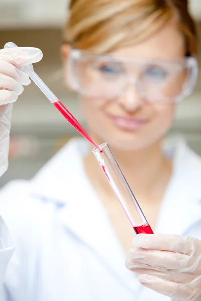 Close-up de uma cientista feminina colocando líquido em um tubo de ensaio sagacidade — Fotografia de Stock