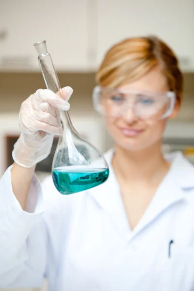 Retrato de una científica brillante mirando un líquido — Foto de Stock