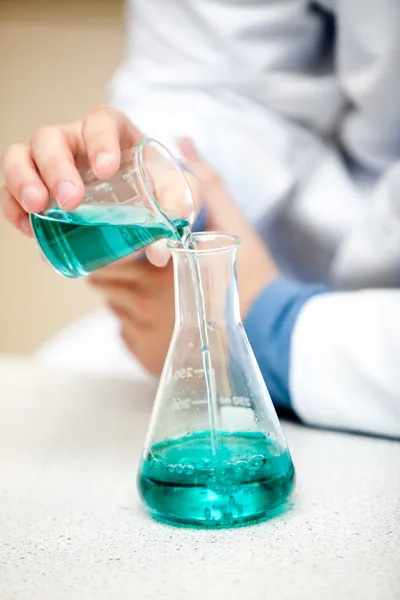 Chemiker gießt eine blaue Flüssigkeit — Stockfoto