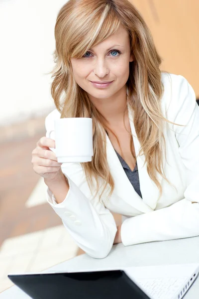 Světlé podnikatelka drží šálek kávy před klína — Stock fotografie
