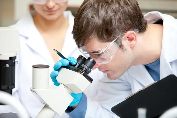 Caucasian male scientist holding pen and clipboard looking throu — Stock Photo, Image
