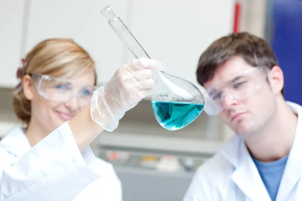 Two serious scientists looking at a blue liquid — Stock Photo, Image