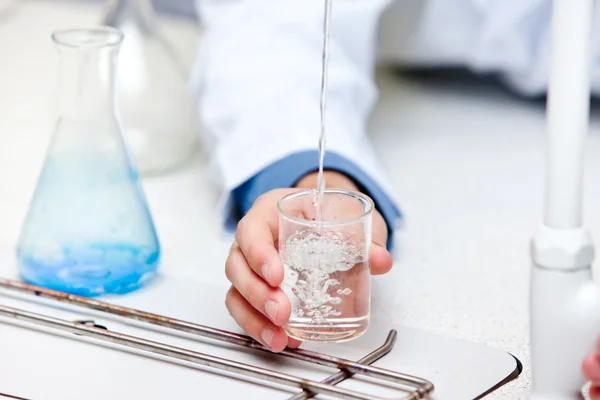 Närbild av en manlig forskare hälla vätskan i en becher — Stockfoto