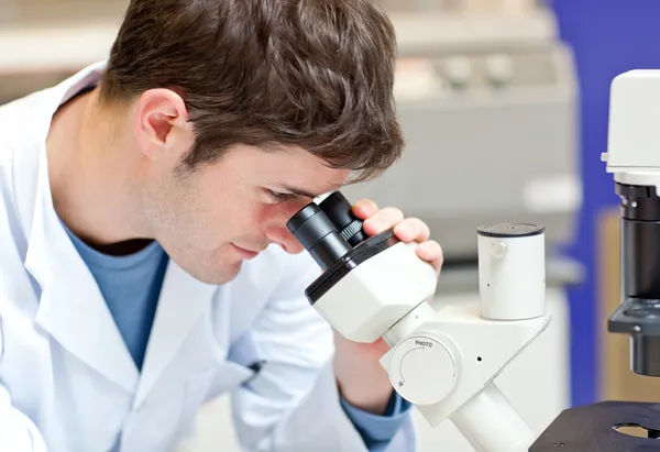 Увлечённый учёный-мужчина смотрит в микроскоп — стоковое фото