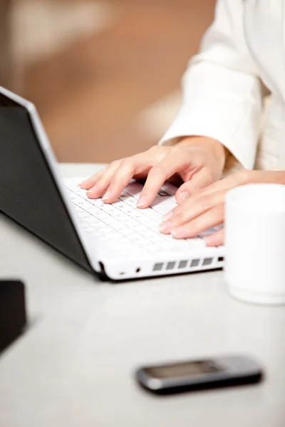 Close-up de uma empresária ocupada usando seu laptop com celular — Fotografia de Stock